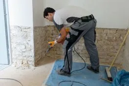 Handwerker entfernt Wandfliesen mit Meißel, Renovierung im Innenraum