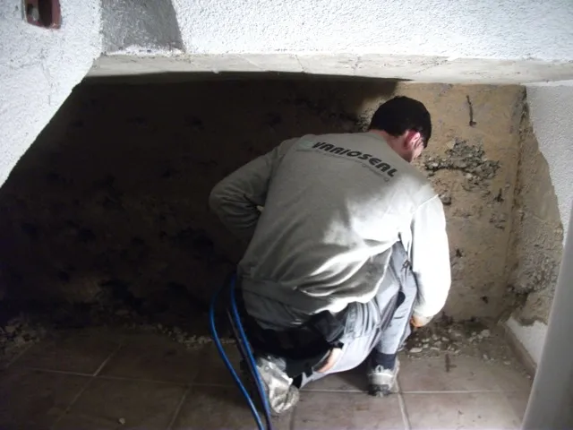 Bauarbeiter saniert feuchte Kellerwand, Injektion gegen Schimmel und Nässe